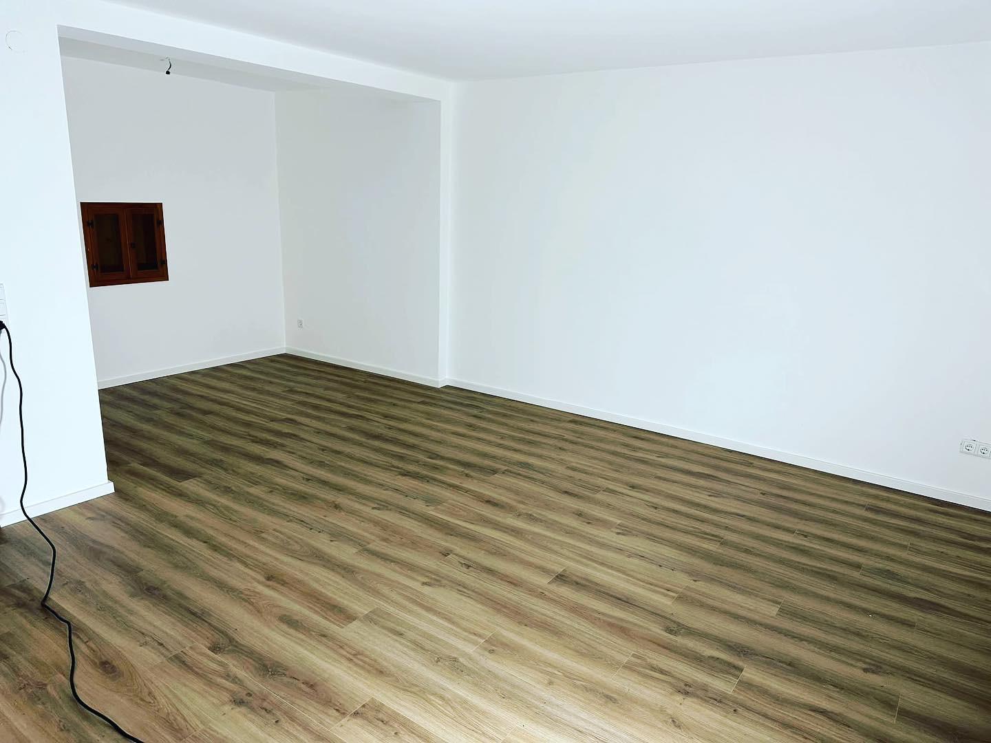 Frisch renovierter Wohnraum mit weißen Wänden und neu verlegtem Vinylboden in Holzoptik – moderner Innenanstrich für helle, gepflegte Wohnatmosphäre.