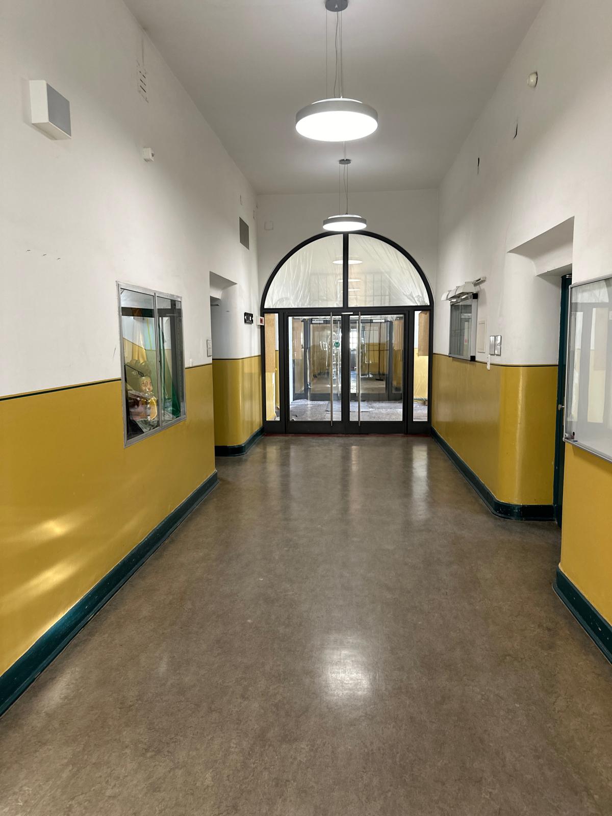 Frisch renovierter Flur mit zweifarbigem Innenanstrich in Weiß und Gelb – professionelle Malerarbeiten für ein gepflegtes und freundliches Raumambiente in einem öffentlichen Gebäude.